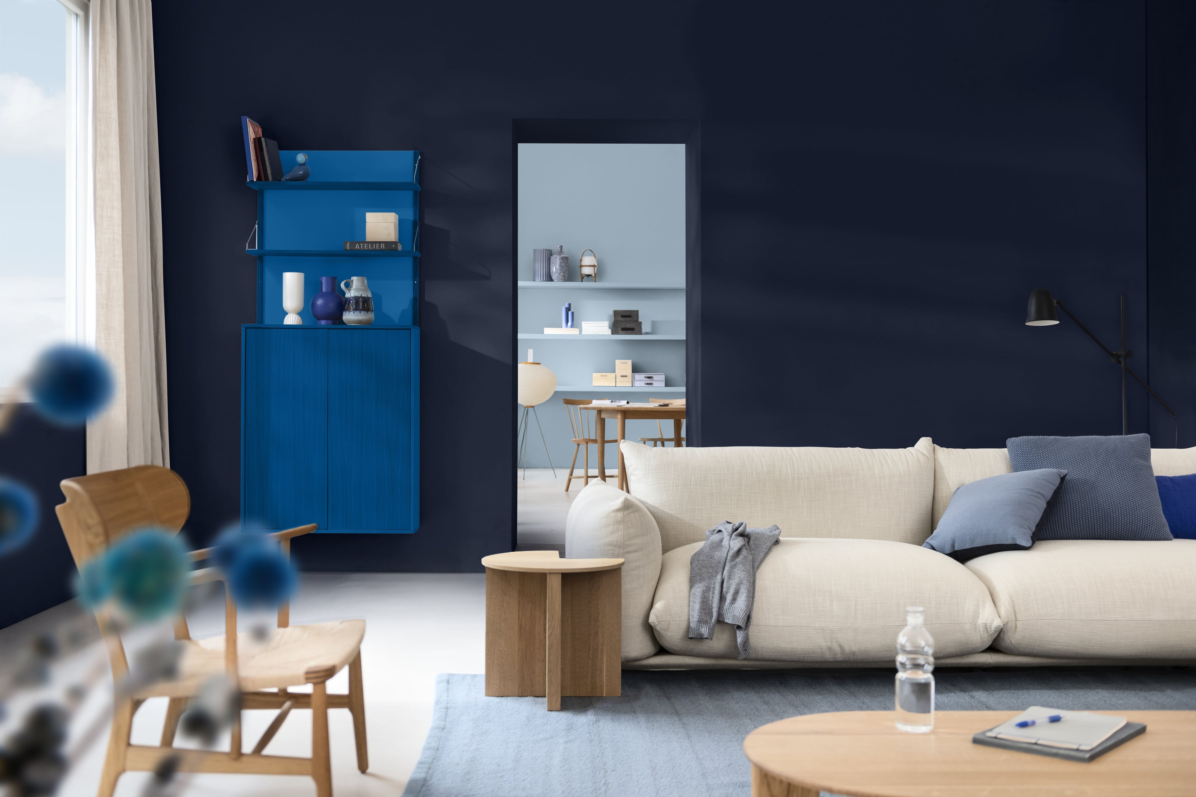 Woonkamer met blauw geschilderde muren, witte bank en houten kast