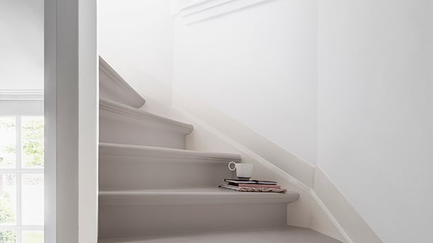 Een lichte trap met lichtgekleurde treden en een kleine stapel boeken op de trap.