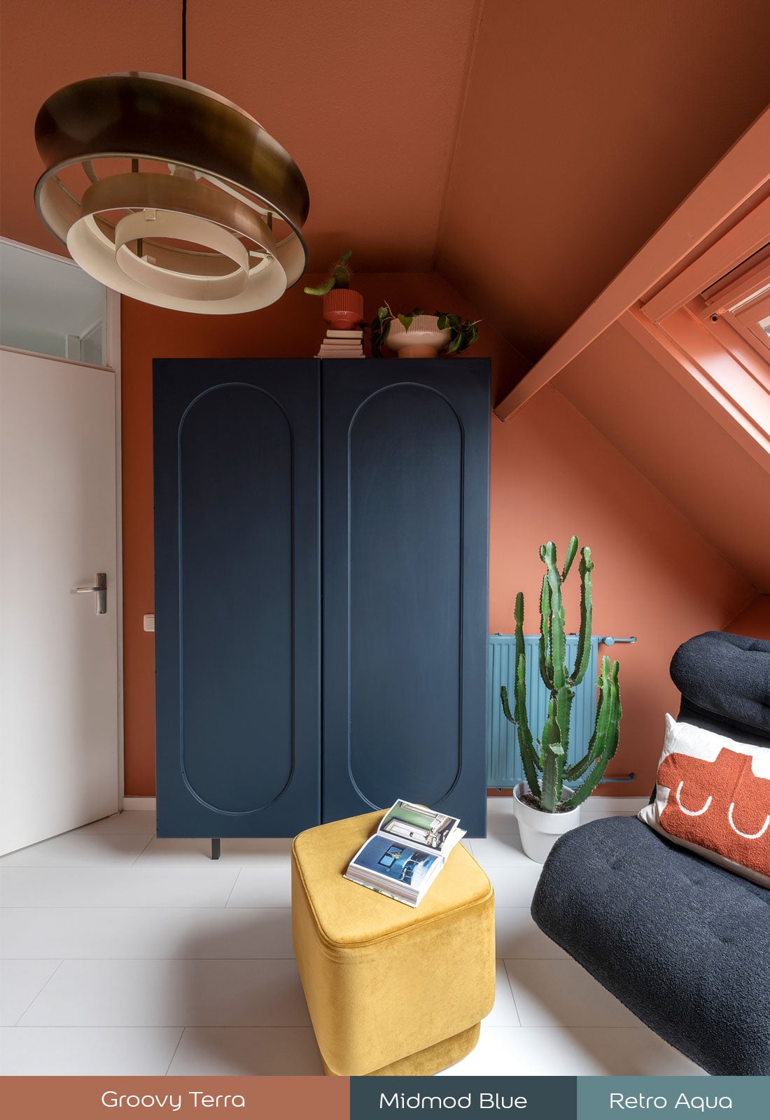 Slaapkamerhoek met donkerblauwe kast, terracotta muren, gele poef en een grote cactus