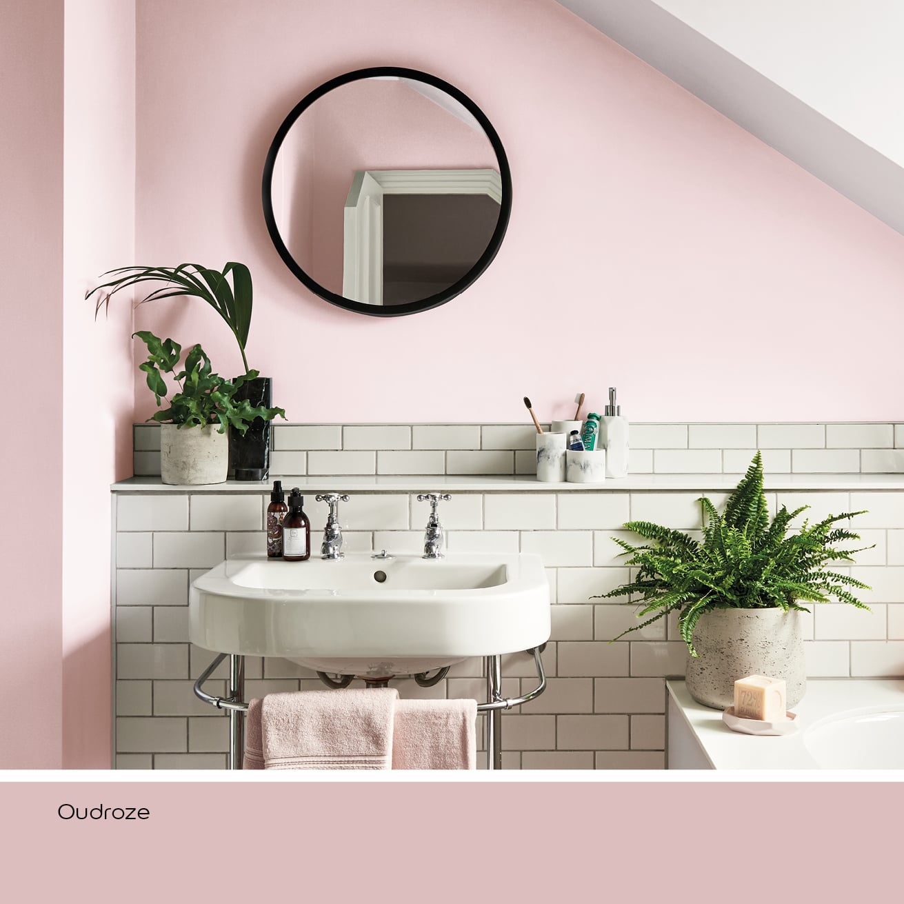 Badkamer met oudroze muur, witte wastafel en groene planten