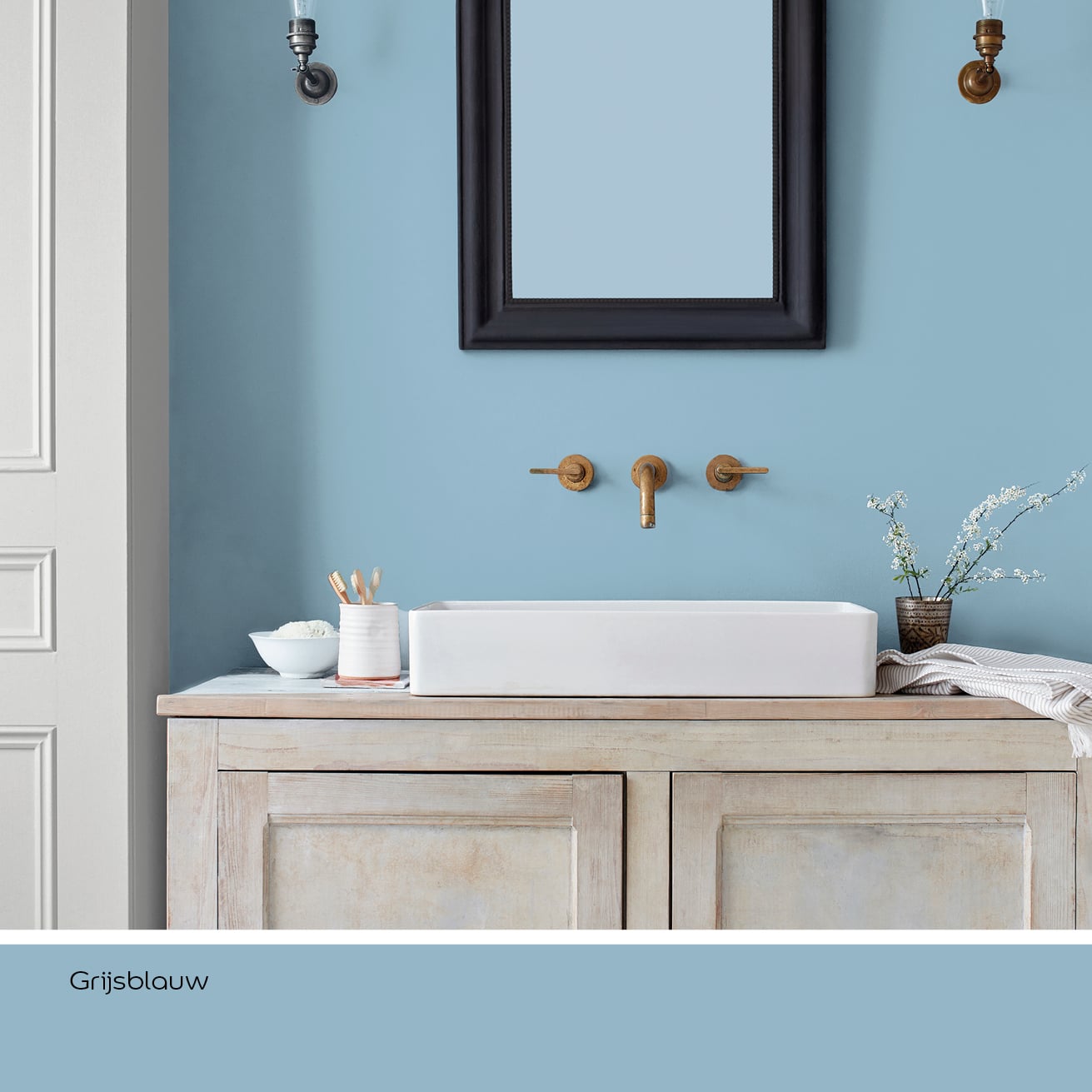Badkamer met lichtblauwe muur, houten wastafelmeubel en witte waskom