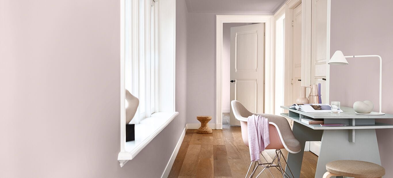 Pastelwerkplek met een bureau, stoelen en lichtroze muren.