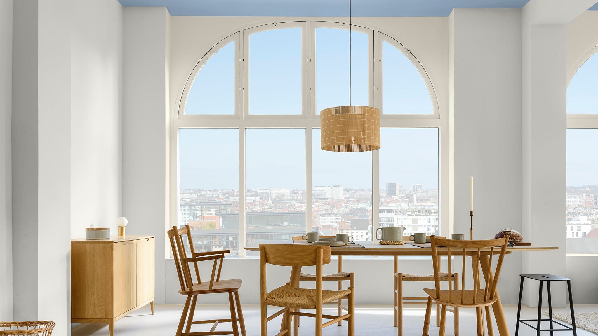 Lichtblauw plafond in woonkamer met neutrale muren en grote boogramen