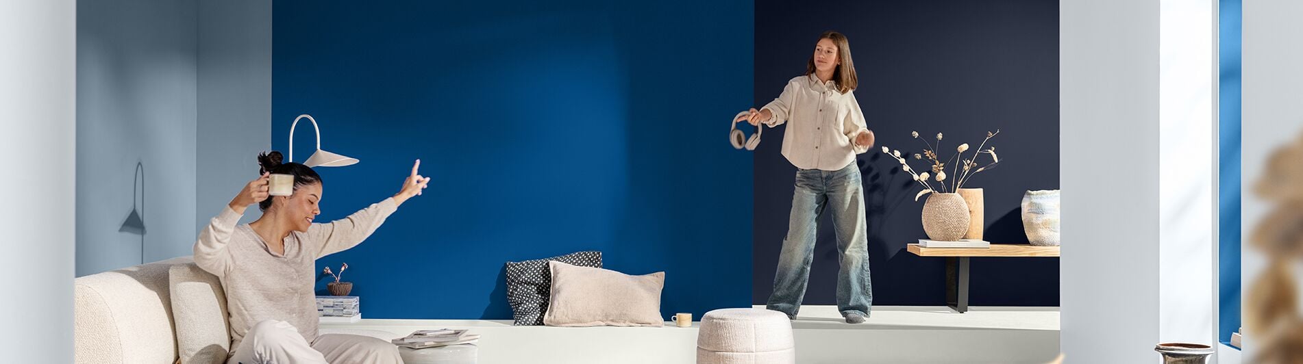Twee personen die van muziek genieten in een moderne kamer met diepblauwe muren.